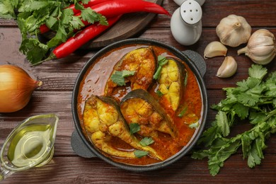 Photo of Tasty fish curry and ingredients on wooden table, flat lay. Indian cuisine