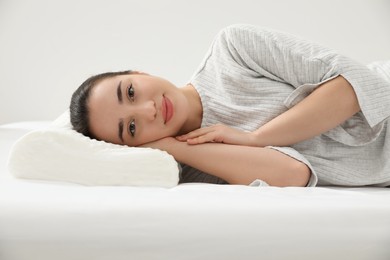 Photo of Woman lying on orthopedic memory foam pillow indoors