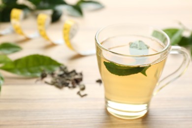 Photo of Herbal diet tea and measuring tape on wooden table. Space for text