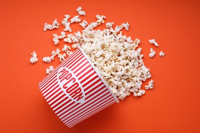 Photo of Bucket of tasty popcorn on orange background, flat lay