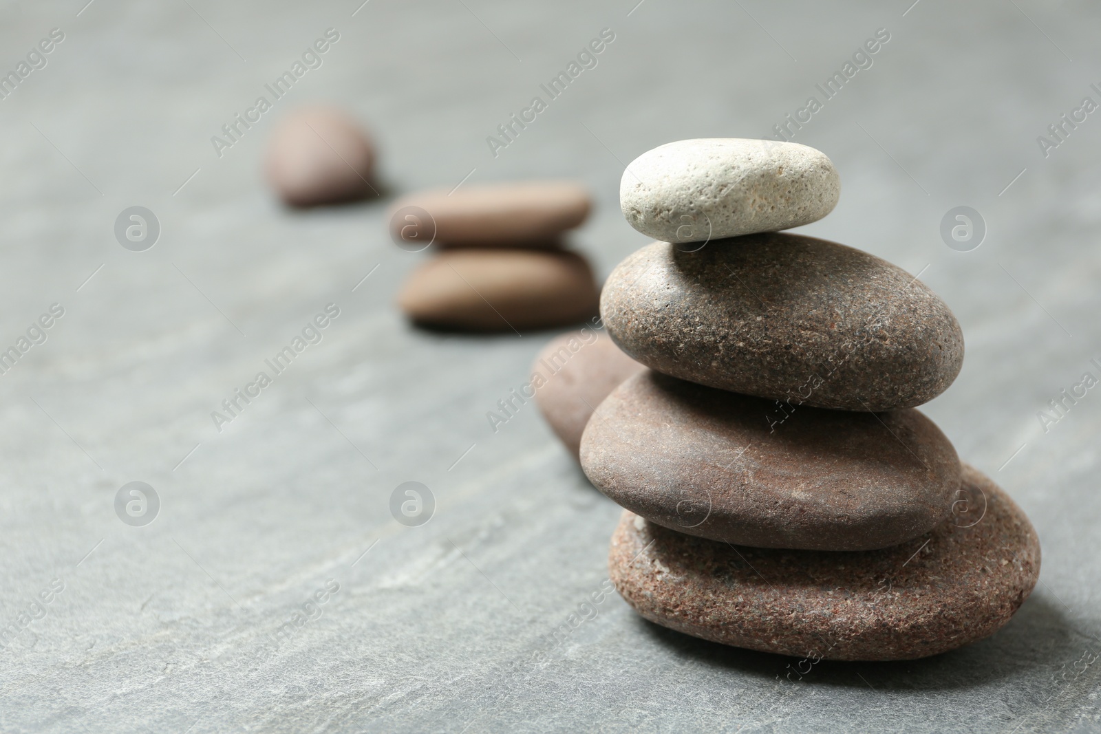 Photo of Stacked spa stones on grey table. Space for text