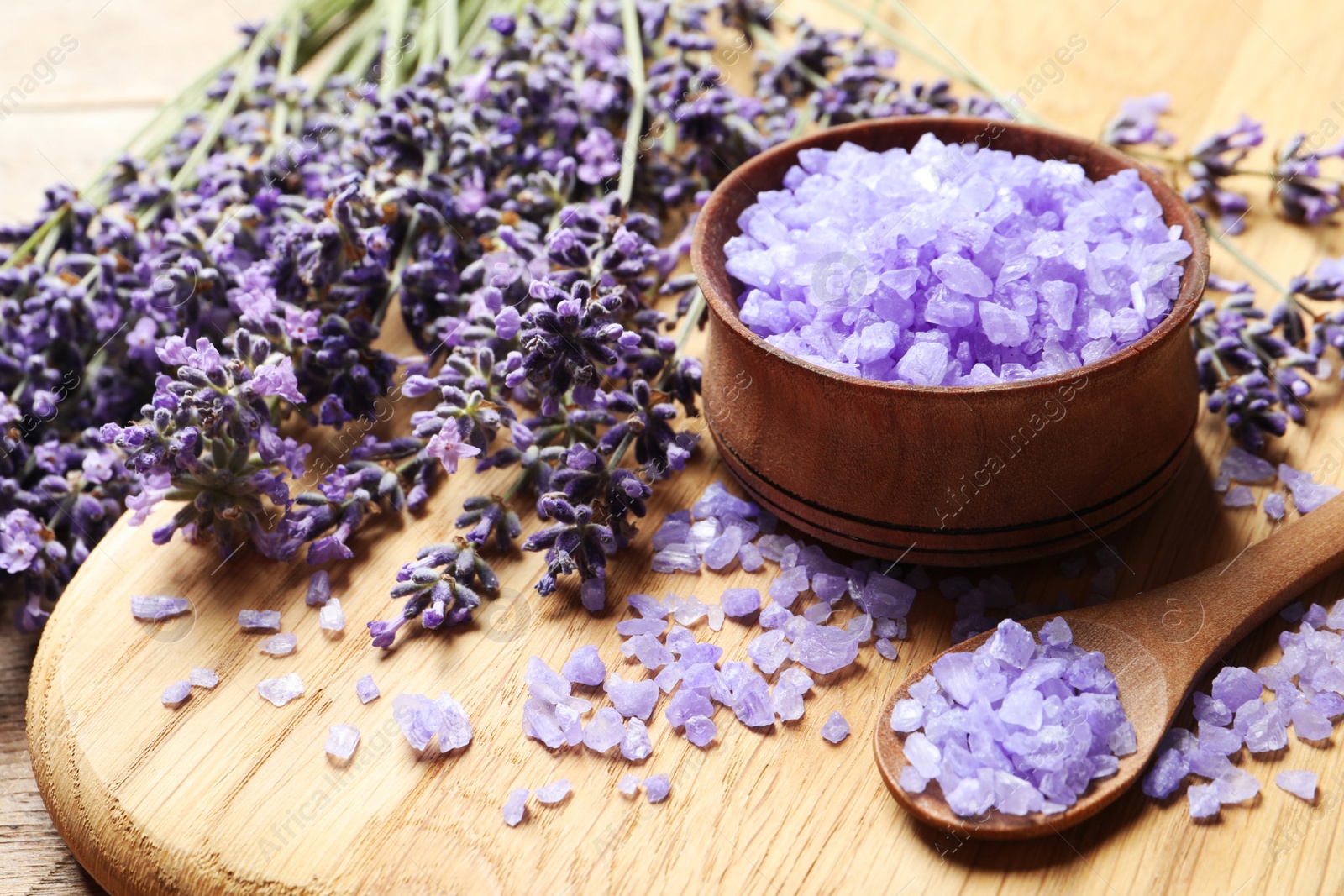 Photo of Wooden board with natural lavender bath salt and flowers on table. Cosmetic product