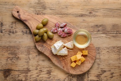 Photo of Toothpick appetizers. Pieces of sausage, cheese and honey on wooden table, top view