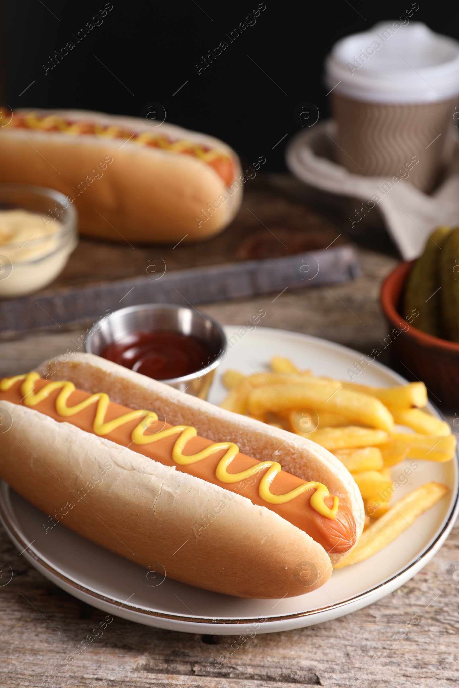 Photo of Delicious hot dog with ketchup, mustard and French fries on wooden table, closeup