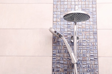 Photo of Shower heads on tiled wall in bathroom. Space for text
