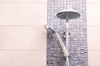 Shower heads on tiled wall in bathroom. Space for text