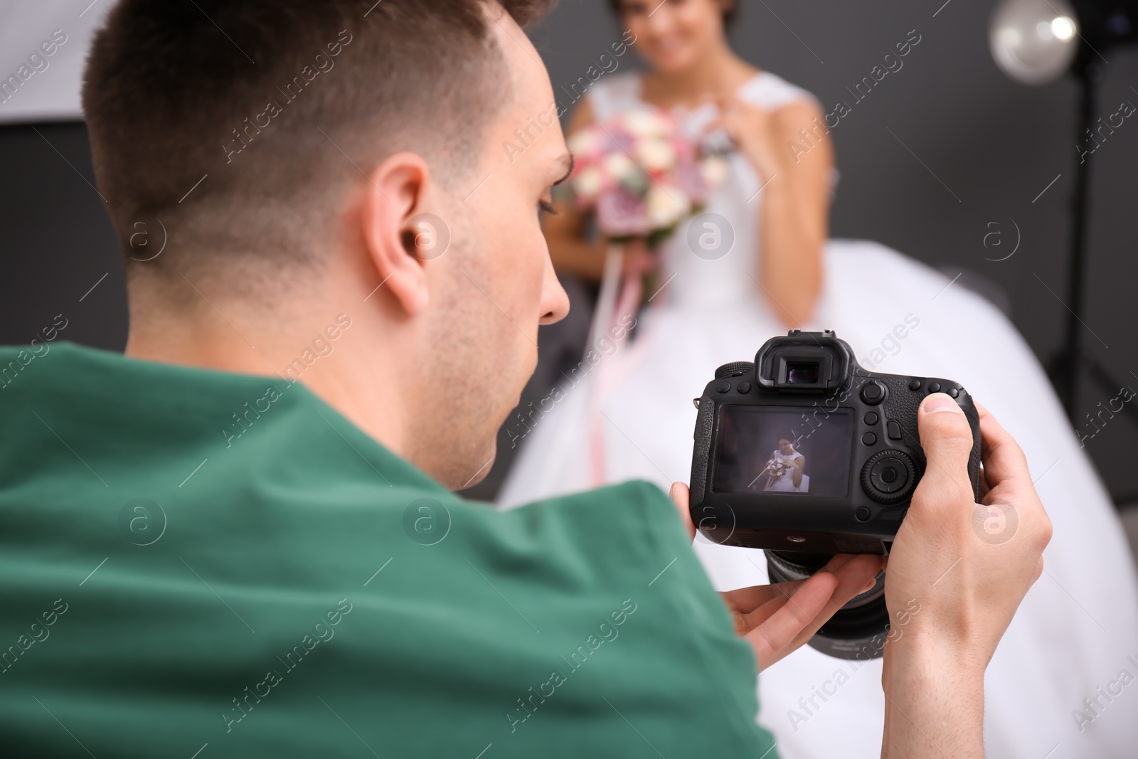 Photo of Professional photographer with camera and beautiful bride in studio