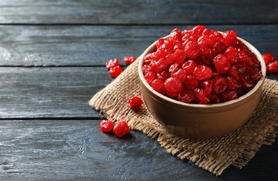 Bowl with tasty cherries on wooden background, space for text. Dried fruits as healthy food