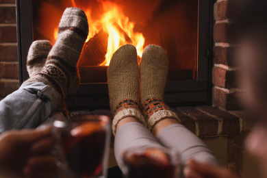 Couple resting near fireplace indoors, closeup. Winter vacation