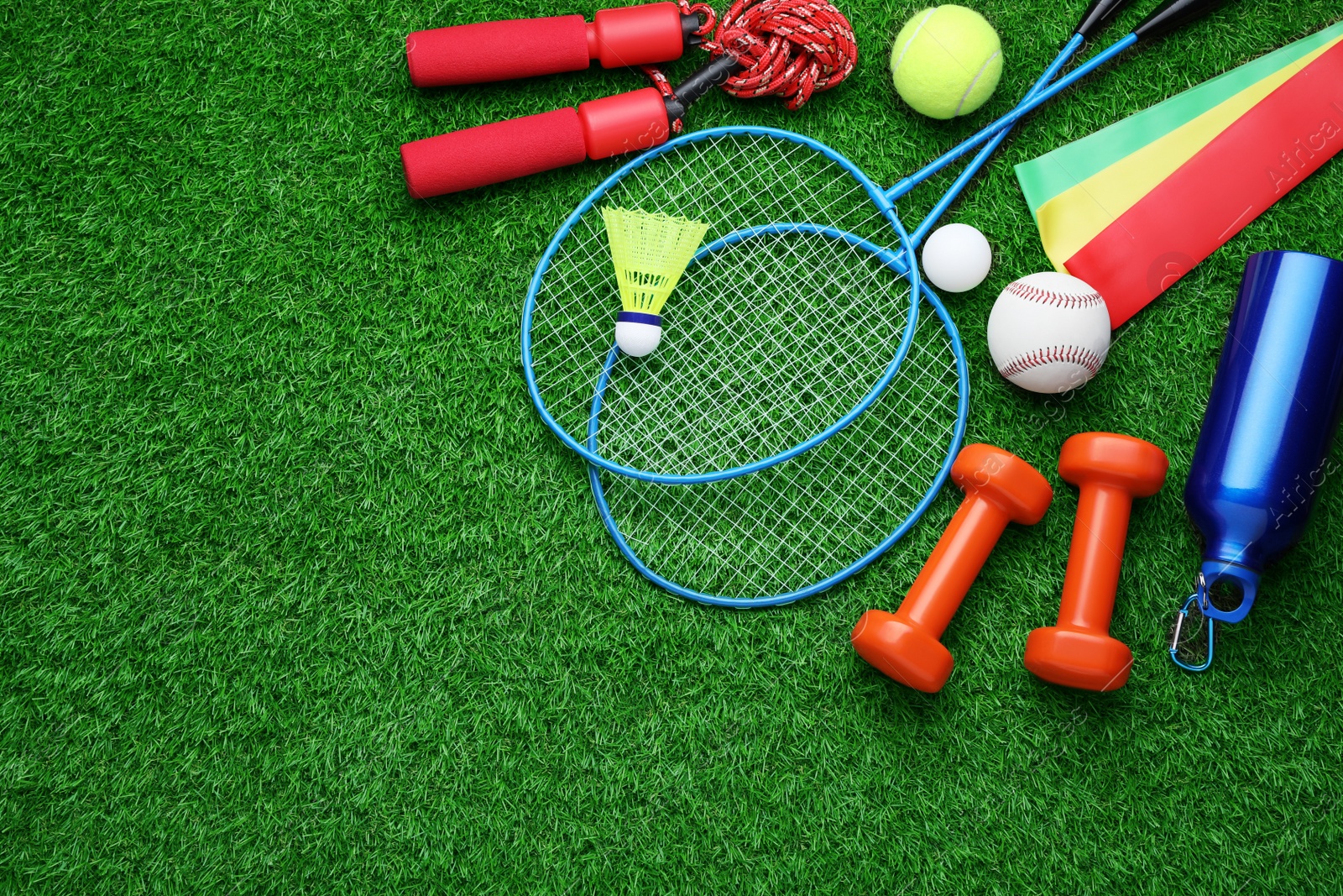 Photo of Set of different colorful sports equipment on green grass, flat lay. Space for text