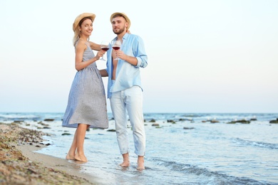 Young couple with glasses of wine on beach