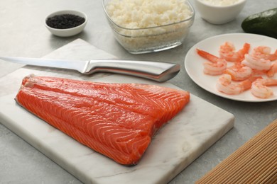 Photo of Fresh salmon and other ingredients for sushi on grey marble table, closeup