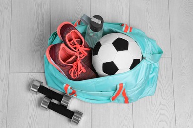 Photo of Bag with different sports equipment on wooden floor, flat lay