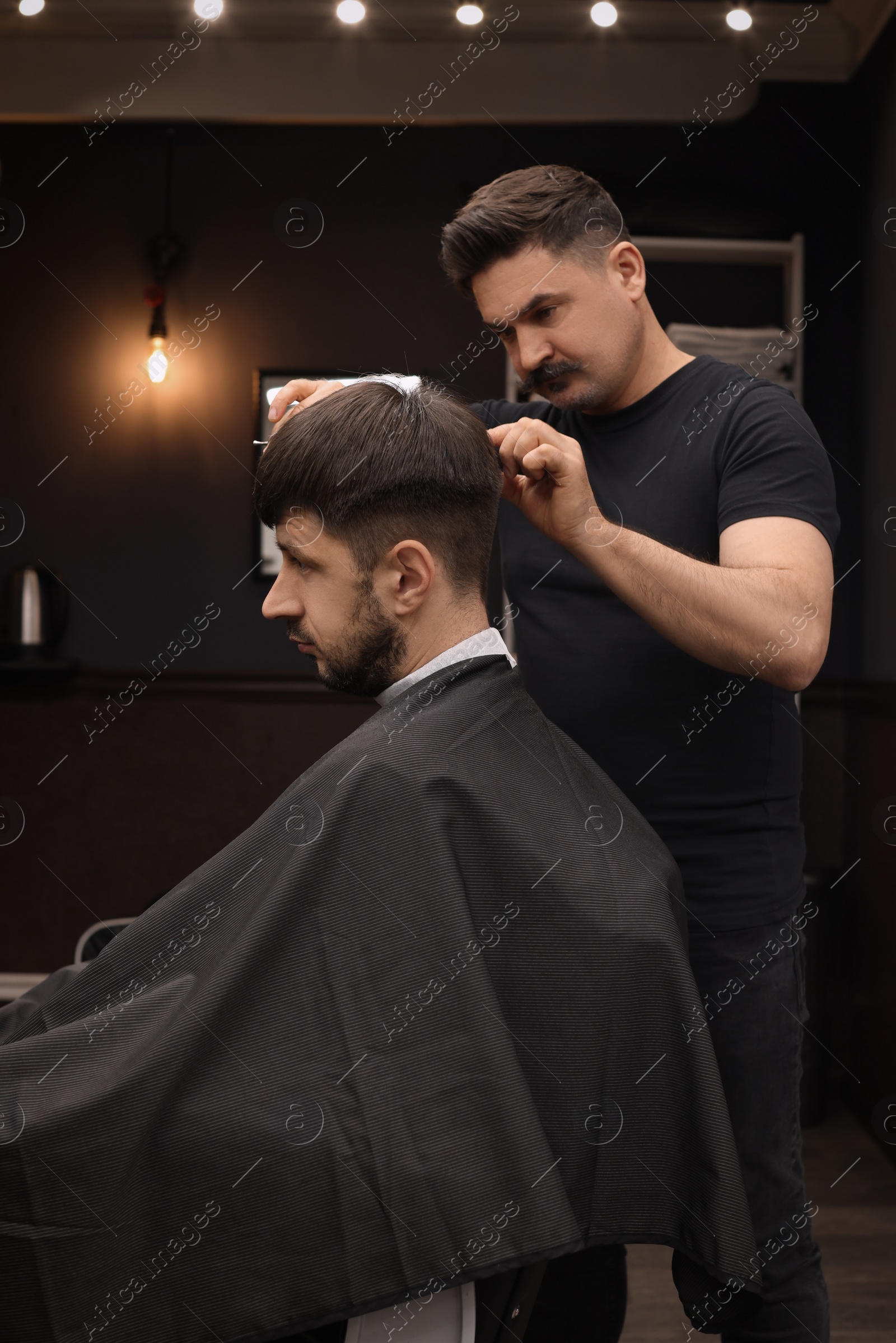 Photo of Professional hairdresser making stylish haircut in barbershop