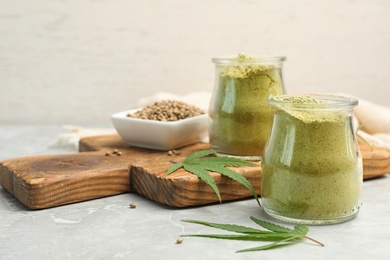 Composition with jars of hemp protein powder on light table. Space for text