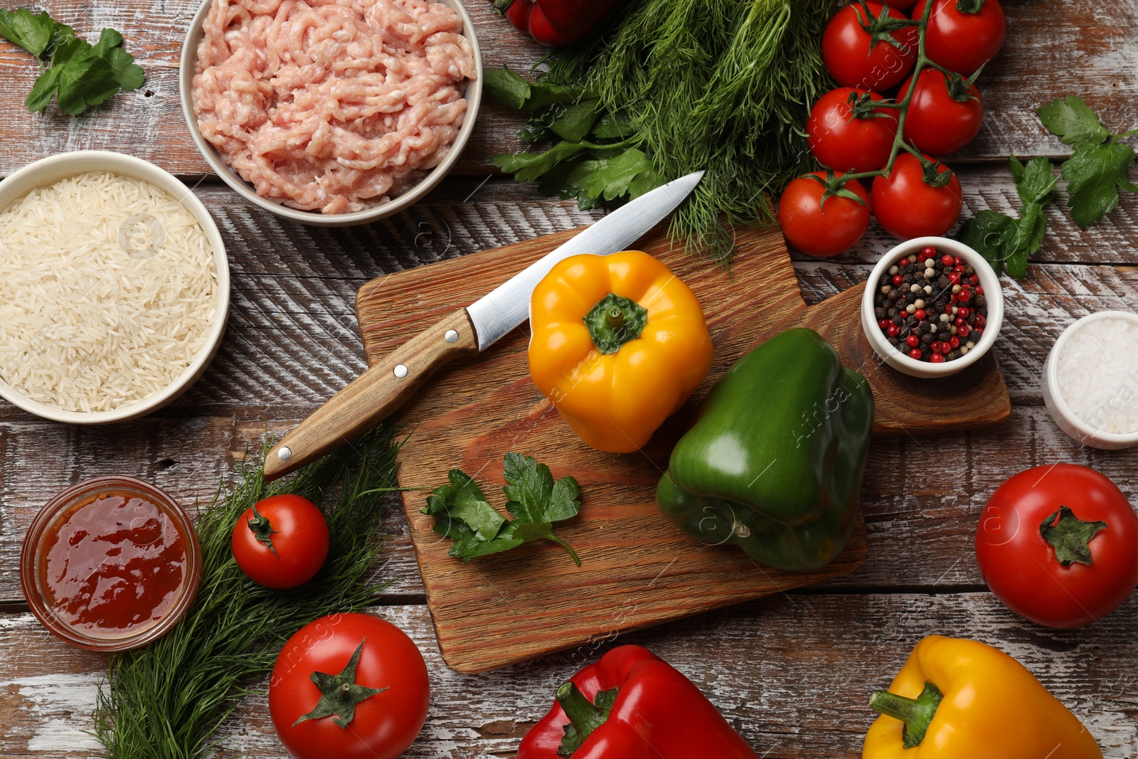 Photo of Making stuffed peppers. Ground meat and other ingredients on wooden table, flat lay