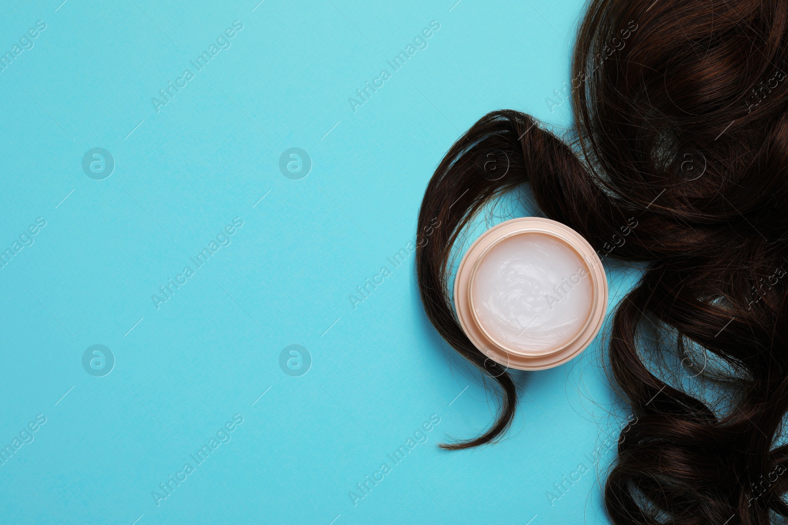 Photo of Lock of healthy brown hair and cosmetic product on turquoise background, flat lay. Space for text
