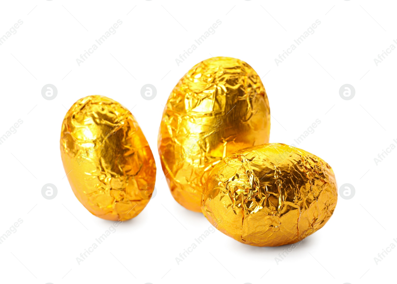 Photo of Chocolate eggs wrapped in bright golden foil on white background