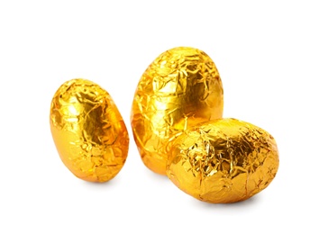 Chocolate eggs wrapped in bright golden foil on white background