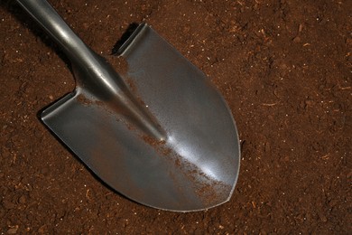 Photo of Metal shovel on fertile soil, top view. Gardening tool