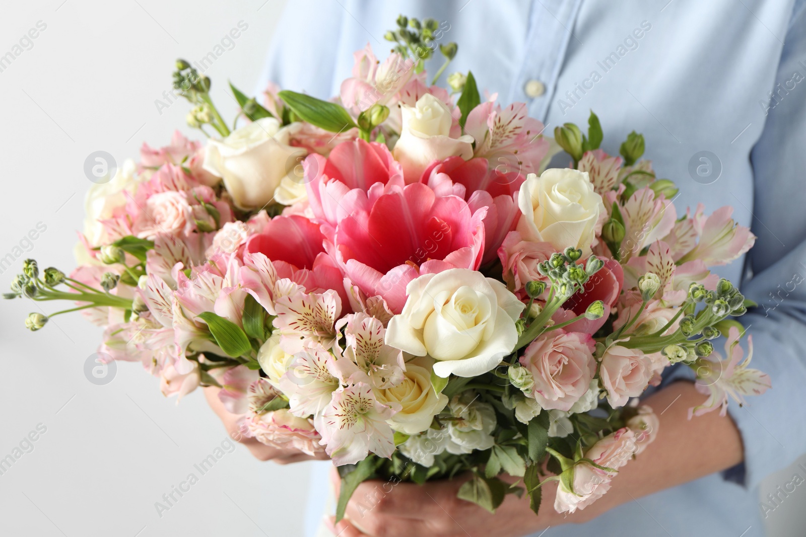 Photo of Woman with beautiful bouquet of fresh flowers on light background, closeup