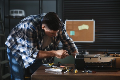 Repairman with screwdriver fixing modern printer in office