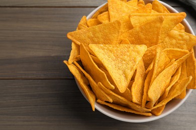 Photo of Tortilla chips (nachos) in bowl on wooden table, top view