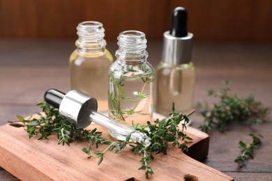 Thyme essential oil on wooden table, closeup