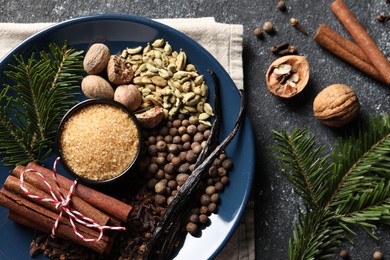 Different aromatic spices and fir branches on grey textured table, flat lay