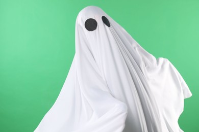 Creepy ghost. Person covered with white sheet on green background