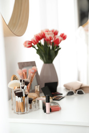 Dressing table with makeup products, accessories and tulips indoors. Interior element