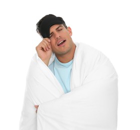 Photo of Man in sleeping mask wrapped with blanket yawning on white background