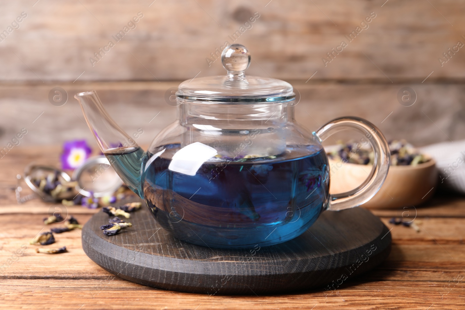 Photo of Organic blue Anchan in glass pot on wooden table. Herbal tea