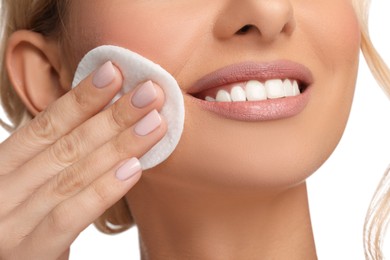 Photo of Smiling woman removing makeup with cotton pad on white background, closeup
