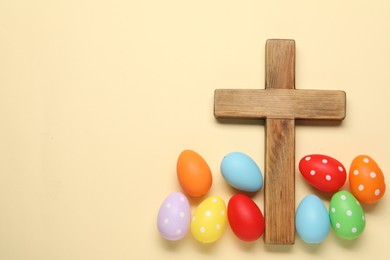 Photo of Wooden cross and painted Easter eggs on beige background, flat lay. Space for text