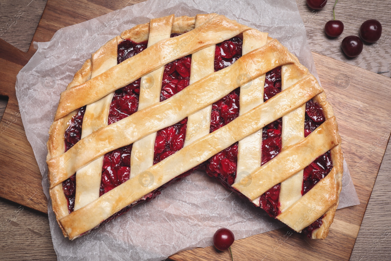 Photo of Delicious fresh cherry pie on wooden board, flat lay