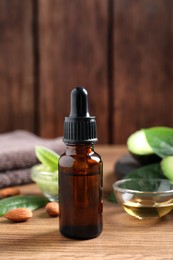 Bottle of essential oil, fresh avocado and almonds on wooden table