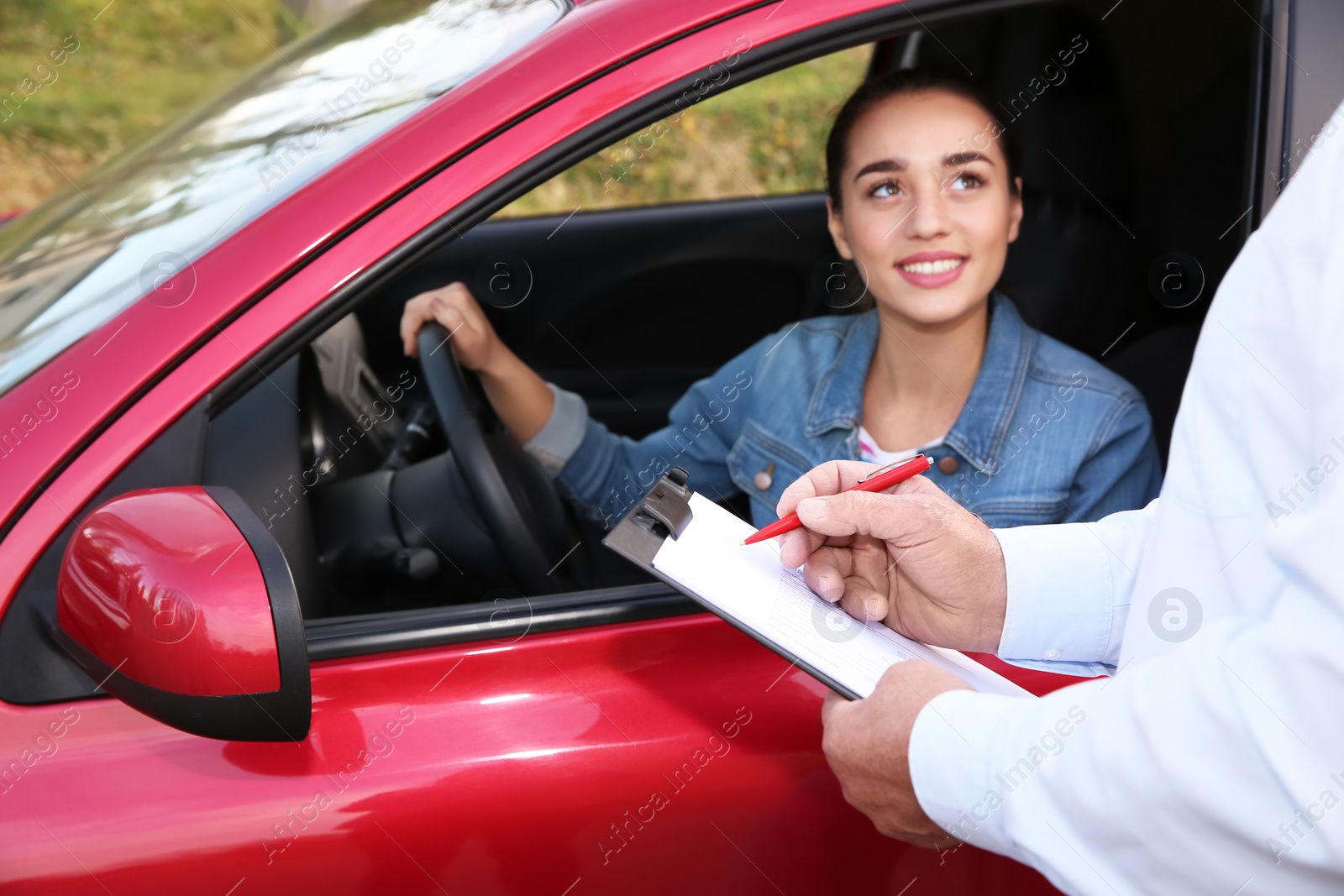 Photo of Instructor near woman in car, outdoors. Passing driving license exam