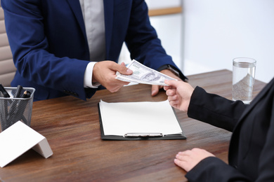 Woman giving bribe money to man at table, closeup