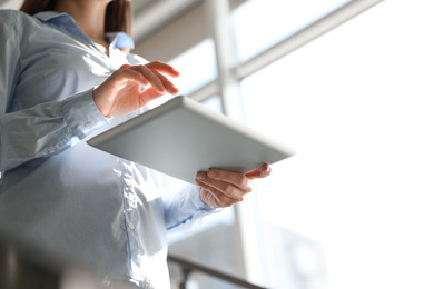 Photo of Closeup view of businesswoman working with modern tablet in office, low angle view