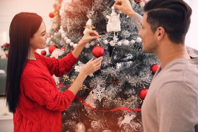 Happy couple decorating Christmas tree at home