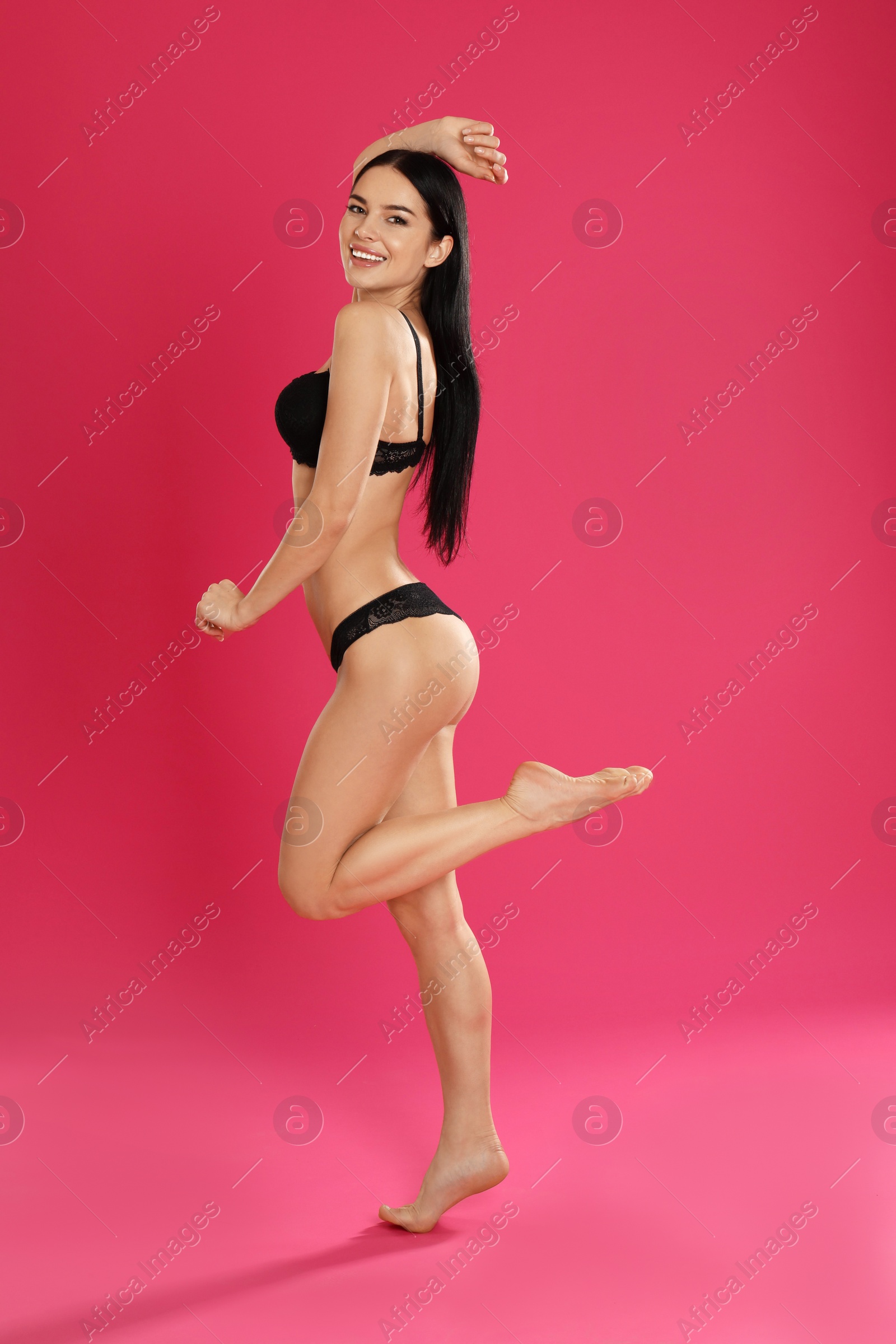 Photo of Beautiful young woman in black underwear on pink background