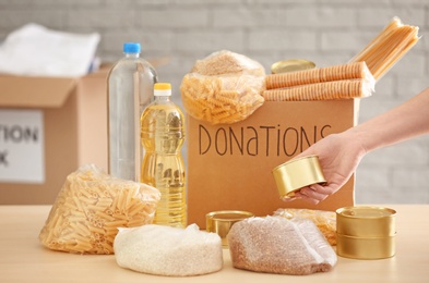 Volunteer collecting food into donation box indoors