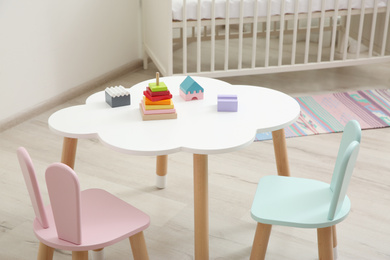 Photo of Little table and chairs with bunny ears in baby room. Interior design