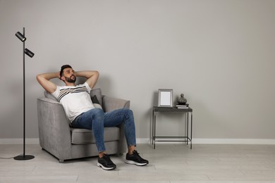 Photo of Man napping in armchair near gray wall, space for text