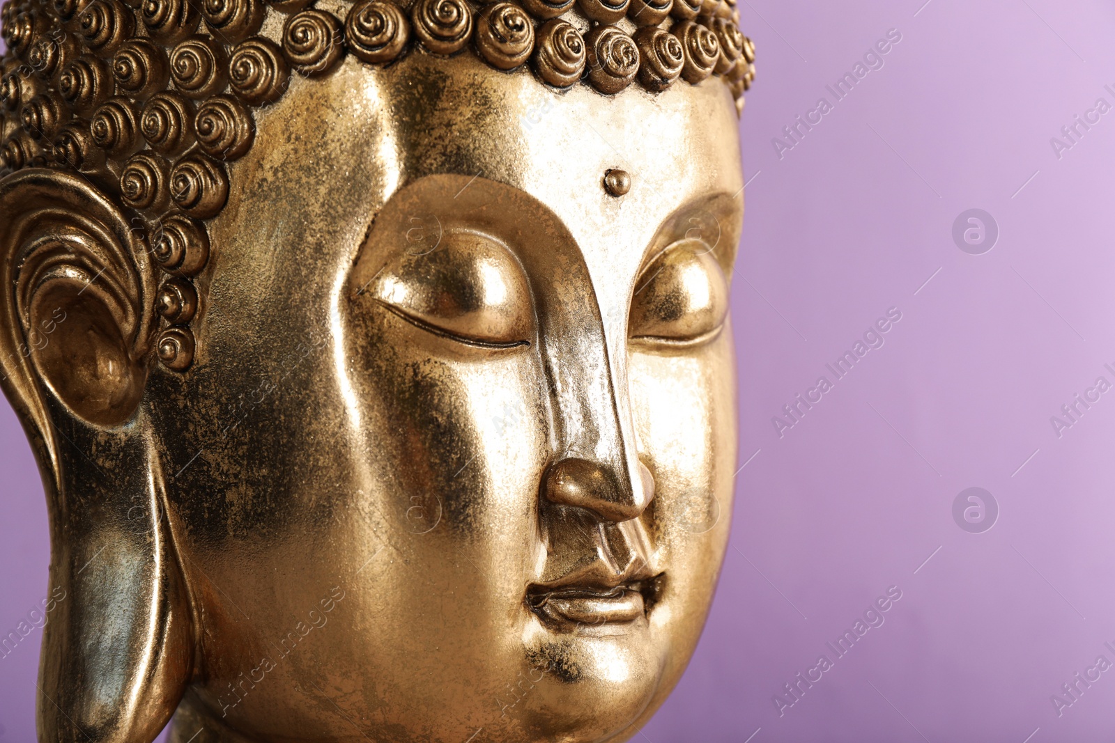 Photo of Beautiful golden Buddha sculpture on violet background, closeup. Space for text