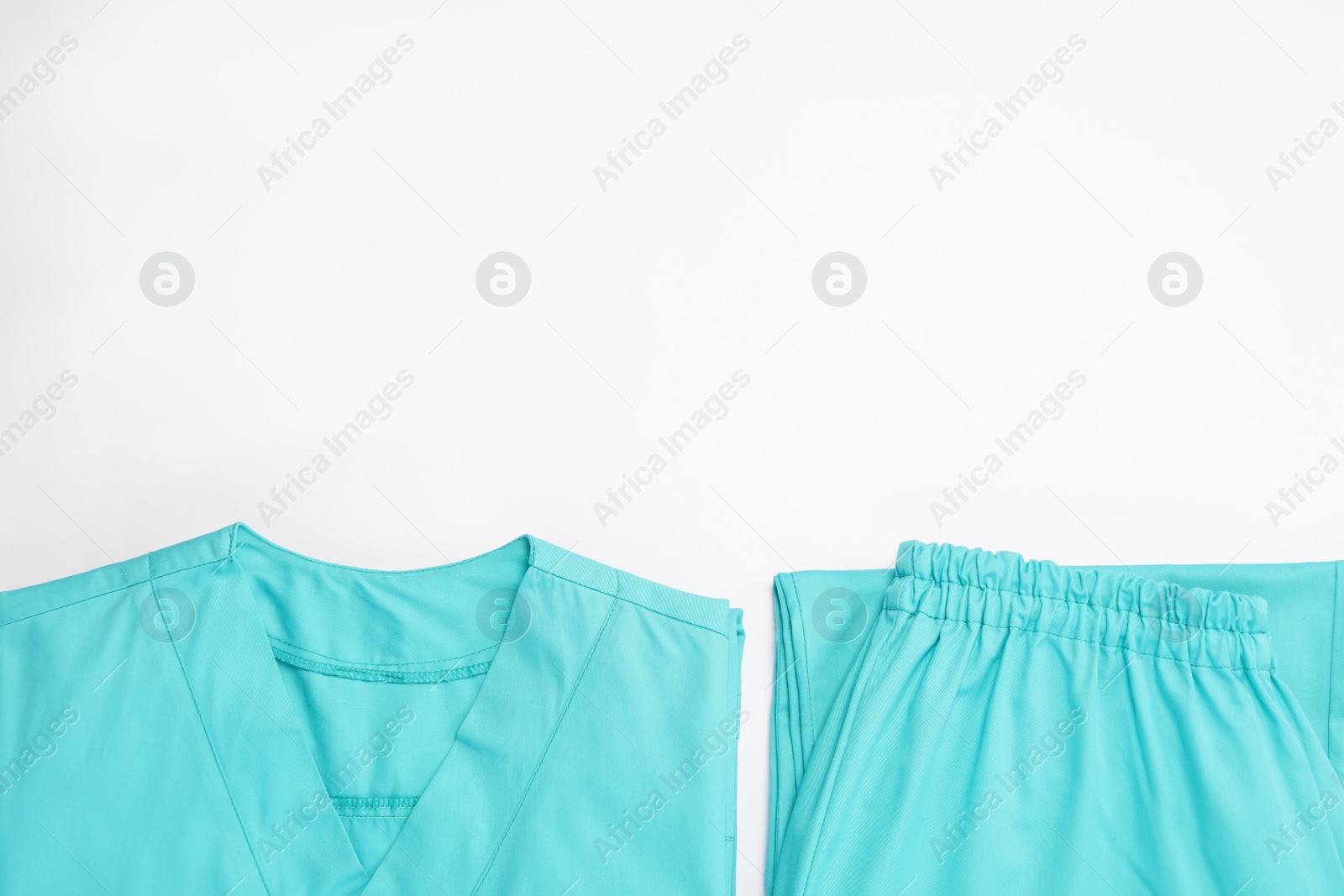 Photo of Light blue medical uniforms on white background, flat lay. Space for text