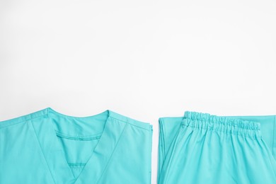 Photo of Light blue medical uniforms on white background, flat lay. Space for text