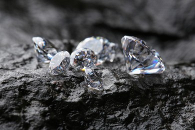 Photo of Different shiny diamonds on wet stone surface, closeup