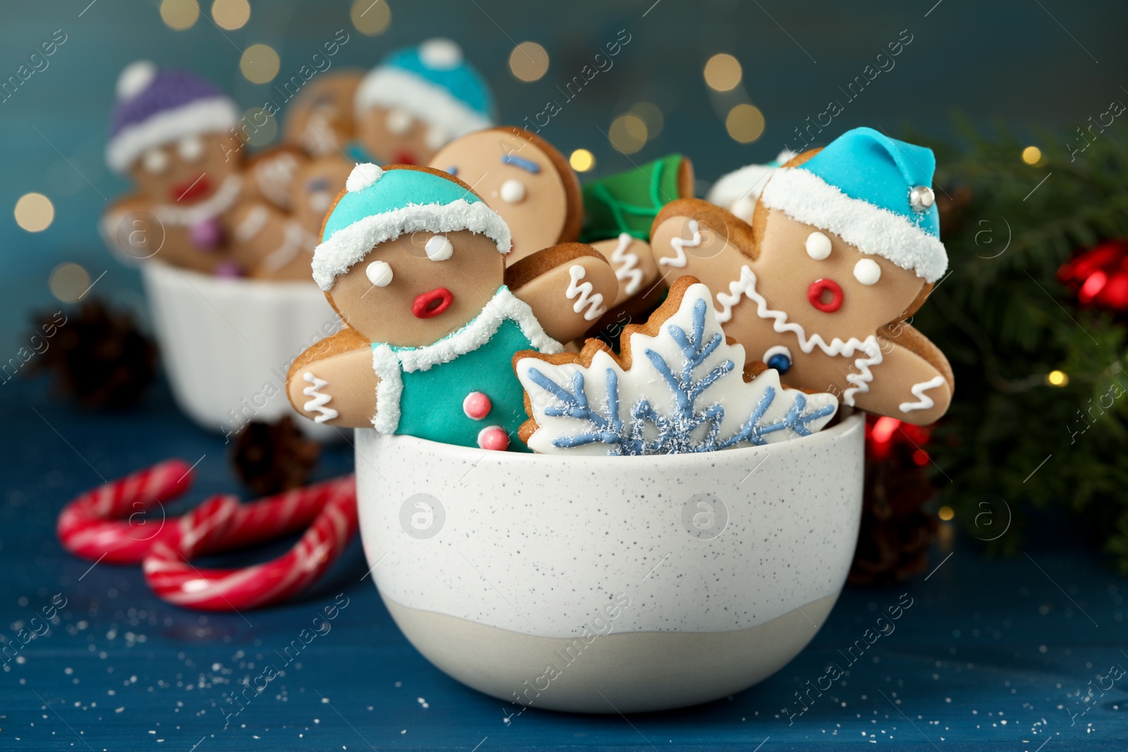 Photo of Delicious homemade Christmas cookies in bowl on blue wooden table against blurred festive lights